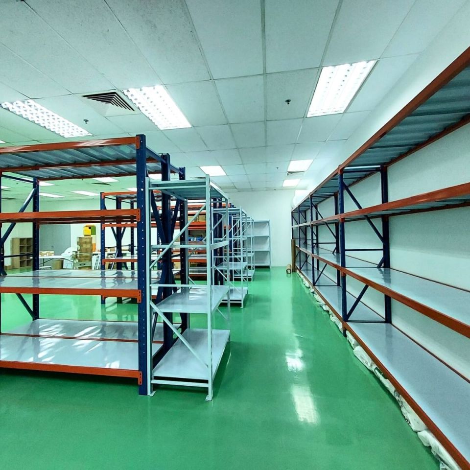 Two long rows of blue and orange industrial racks on a green epoxy warehouse floor